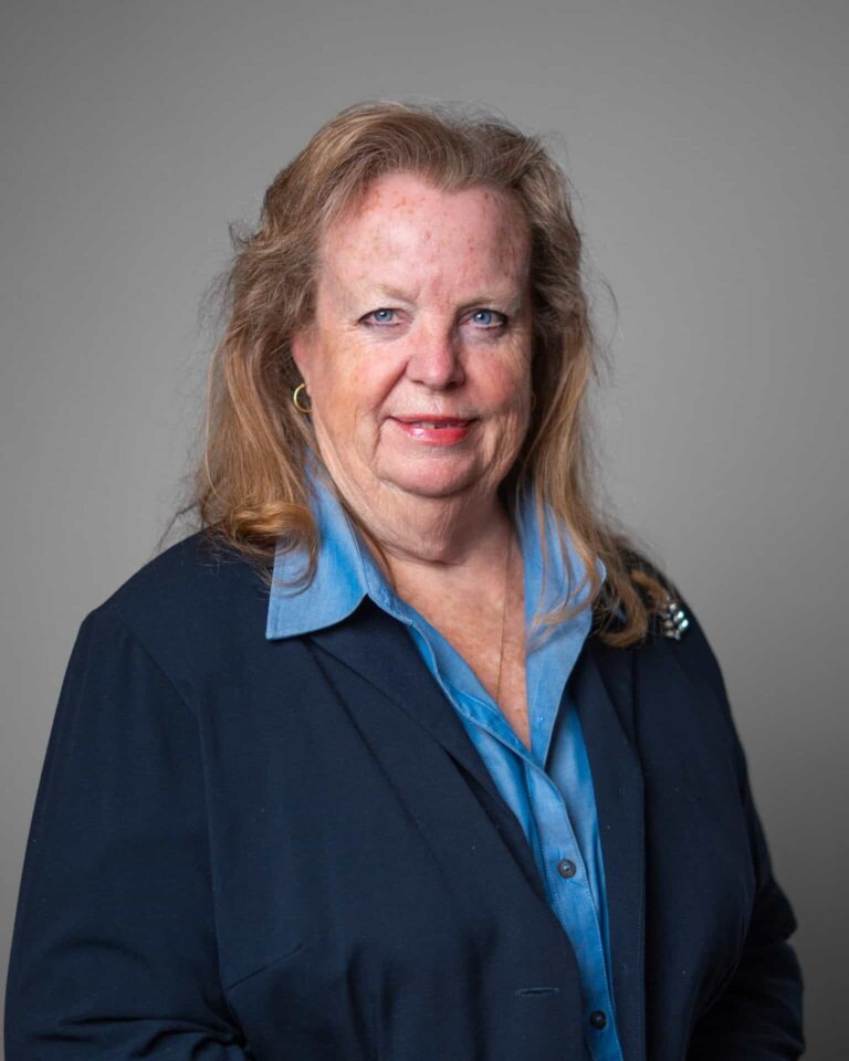 Professional woman in a blue shirt and black blazer, embodying Asset Enterprises' mission to enhance retail technology.