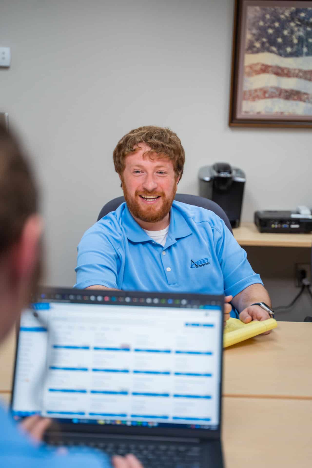Professional discussing managed services program strategy with colleague at desk, enhancing control and predictability.