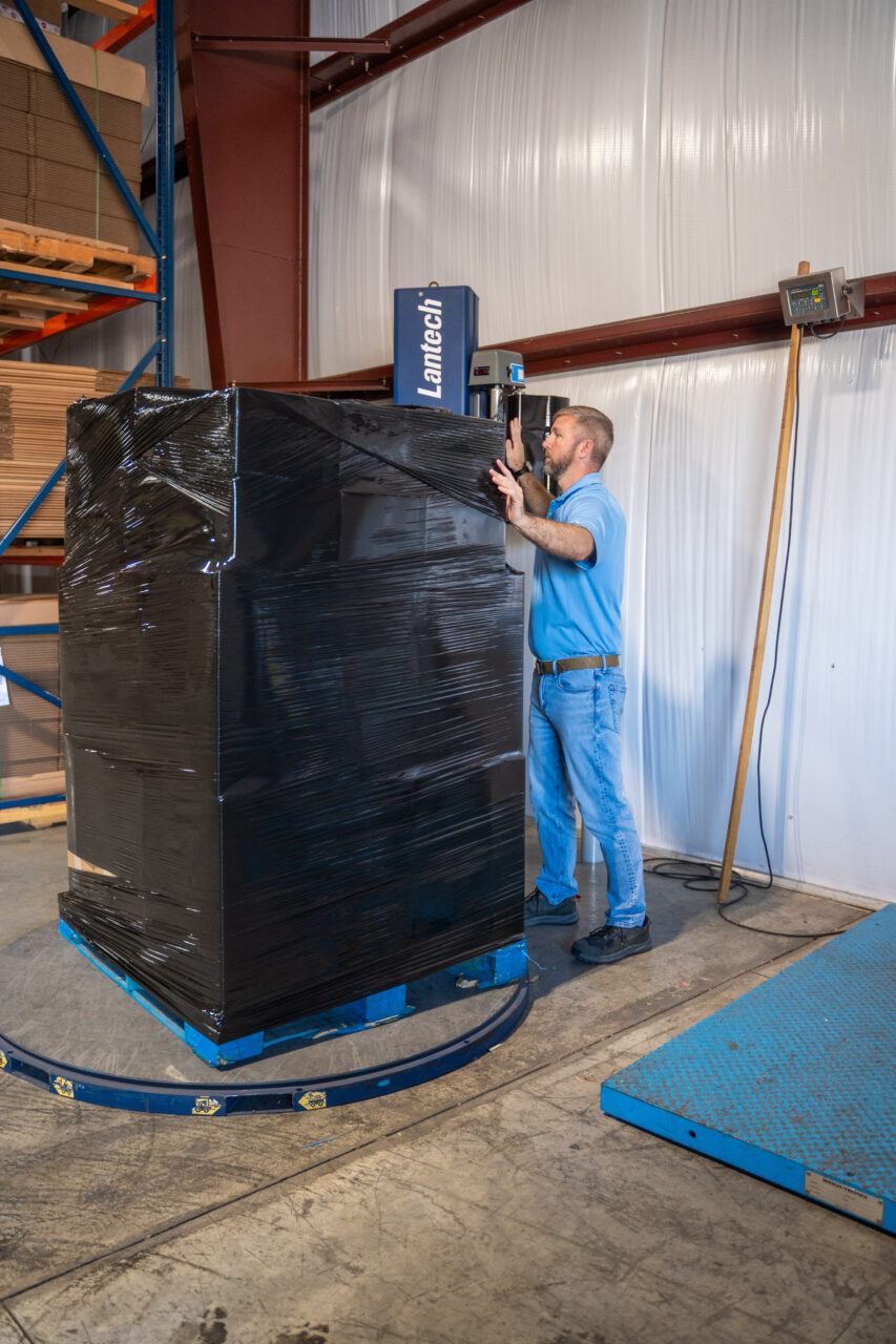 Man in blue securing packaged assets before leaving the site, highlighting secure destruction services.