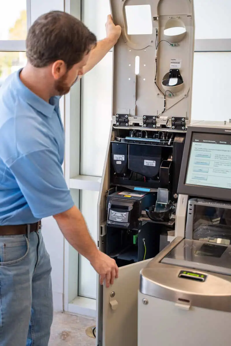 Technician servicing ATM machine, demonstrating tech support in demand for our tech services.