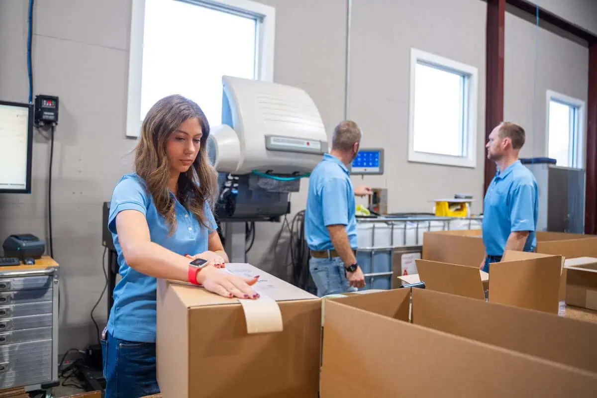 Workers in a warehousing facility, organizing boxes for parts logistics to ensure efficient services execution.