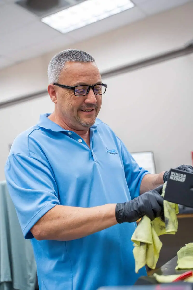 Man in blue polo shirt with Asset Enterprises logo handling warranty claim paperwork efficiently.