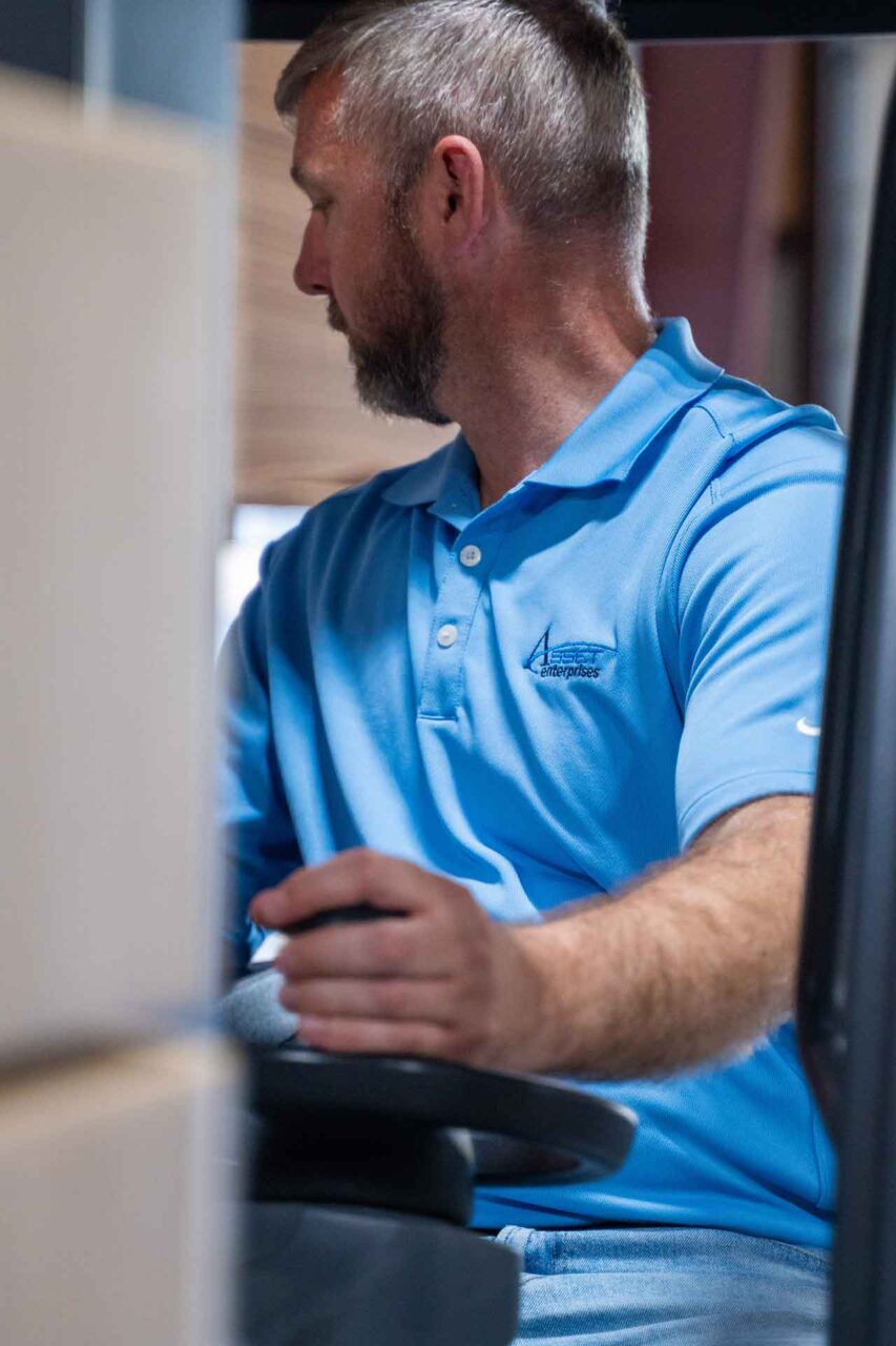 Man in a blue shirt operating machinery, representing consistent operational execution in managed services.