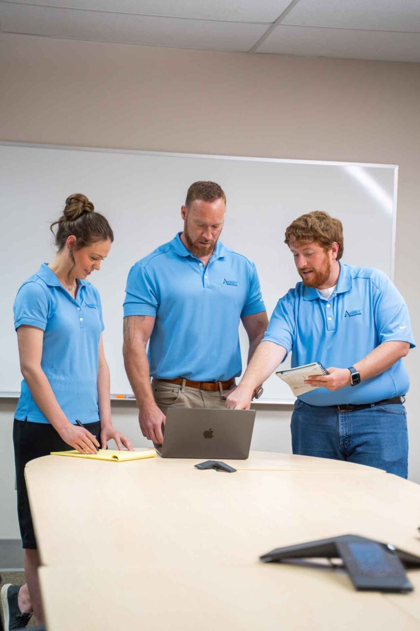 Team discussing asset integration strategy in a meeting room, focusing on laptops and notes for program execution.